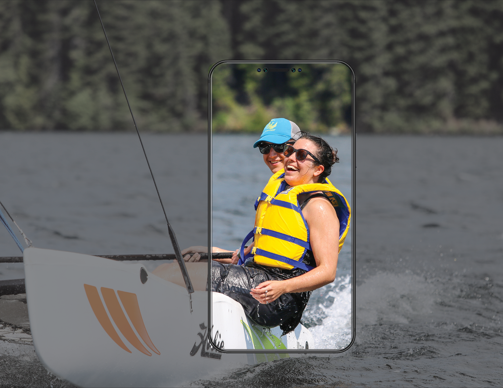 A picture of a male and female on a Hobie Sailboat. The female is laughing and appears to be having a great time. There is a phone frame around the people, showcasing the image.